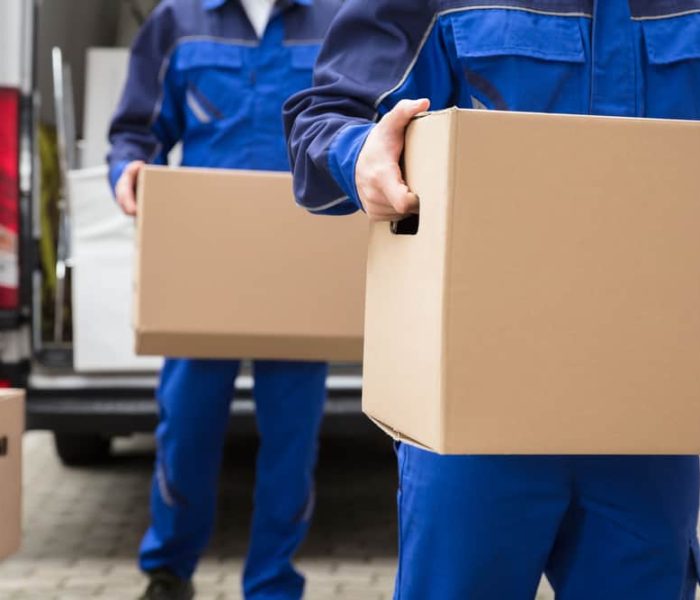 Close-up,Of,Two,Mover's,Hand,In,Uniform,Carrying,Cardboard,Box